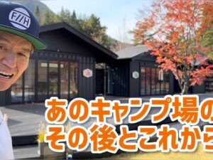 ヒロミが秋の紅葉を背景にしたロケーションで撮影した動画シーン。 カジュアルな服装にキャップをかぶり、笑顔でカメラを見つめるヒロミ、背景には紅葉が美しい木々と建物がある。