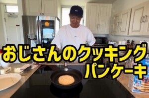 ヒロミが自宅のキッチンで手作りのパンケーキを楽しむ様子。 キッチンでパンケーキを作る男性の動画キャプチャー。男性はカジュアルな服装で、フライパンにパンケーキを焼いているところ。